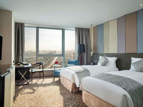 a hotel room with two beds and a large window at Sofitel Lianyungang Suning in Lianyungang