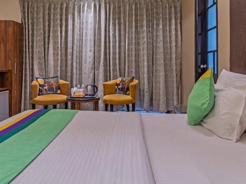 a bedroom with a large bed and two chairs at Hotel Imperial Park in Gurgaon