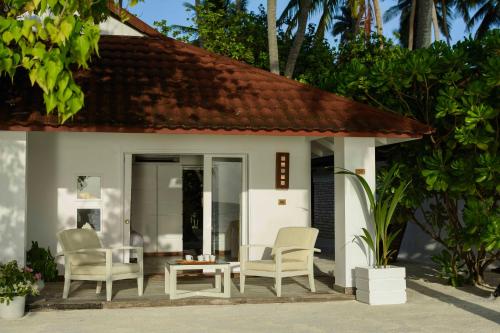 a house with chairs and a table in front of it at Diamonds Thudufushi Maldives Resort & Spa in Thundufushi