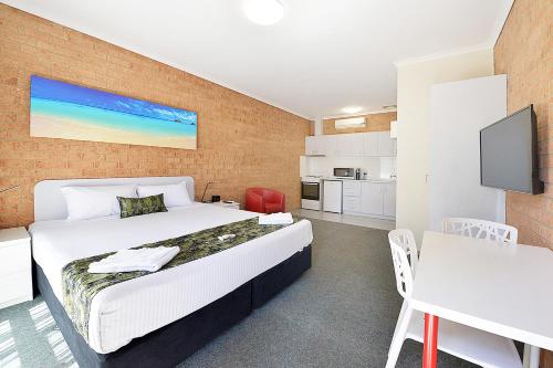 a bedroom with a large bed and a kitchen at Cranbourne Motor Inn in Cranbourne