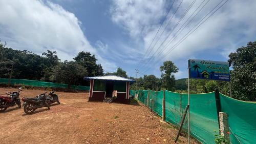 a small building with two motorcycles parked next to a fence at Green home stay in Ankola