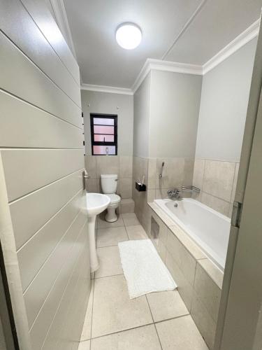 a bathroom with a toilet and a tub and a sink at Zambezi luxe stay in Pretoria
