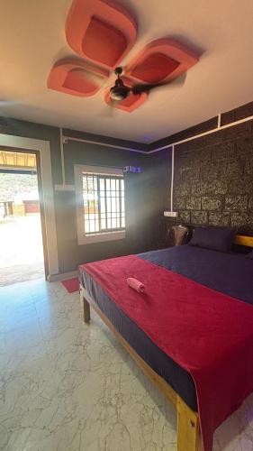 a bedroom with a bed with a ceiling fan at Green home stay in Ankola