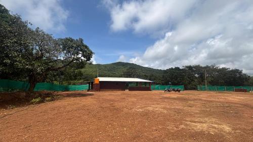a building with a green fence and a dirt field at Green home stay in Ankola