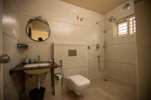 a bathroom with a toilet and a sink and a mirror at Tropica by CBR Farms in Nandigunda