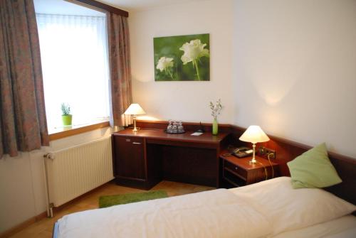 a bedroom with a bed and a desk and a window at Altstadt Hotel Meppen in Meppen
