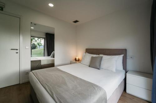 a bedroom with a large white bed and a mirror at Welcome Douro - Eco Camping Resort in Cinfães