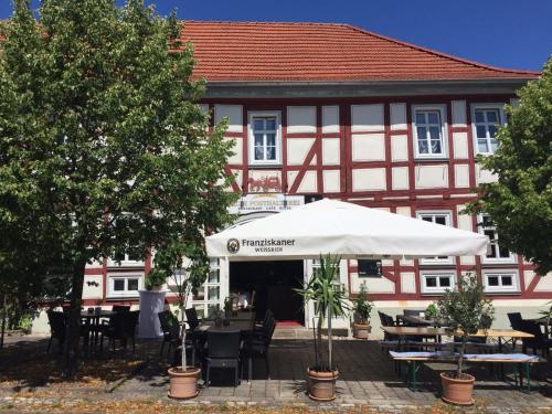a building with a white umbrella and tables and chairs at Hotel Alte Posthalterei in Creuzburg