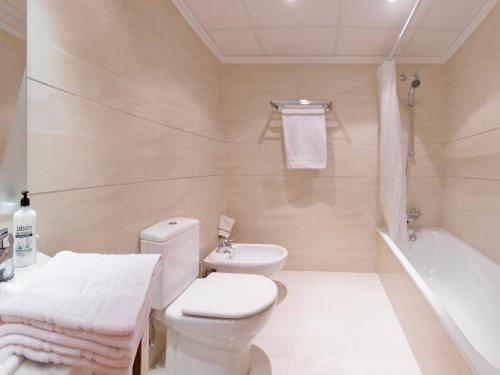 a white bathroom with a toilet and a bath tub at Vilamar VyB in Denia