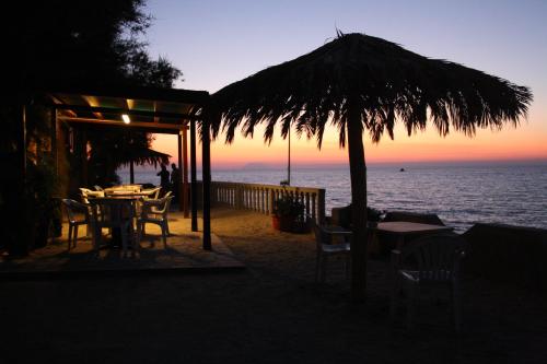 a table and chairs under an umbrella on the beach at Villaggio Camping Fiorina in Capo Vaticano