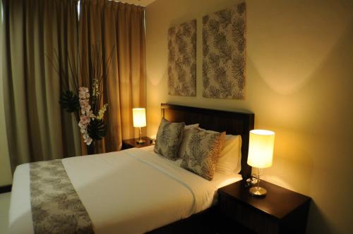 a bedroom with a white bed with two lamps at Marina Oriental Hotel in Butterworth