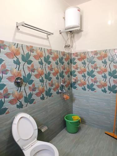 a bathroom with a toilet and flowers on the wall at D 'SOUZA HOLIDAY HOME in Benaulim