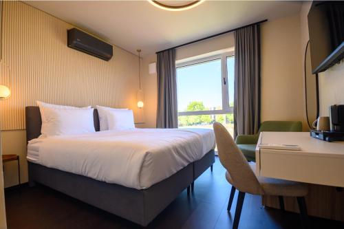 a hotel room with a bed and a desk and a window at Hotel Adore in Ljubljana