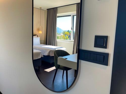 a mirror in a hotel room with a bed and a desk at Hotel Adore in Ljubljana