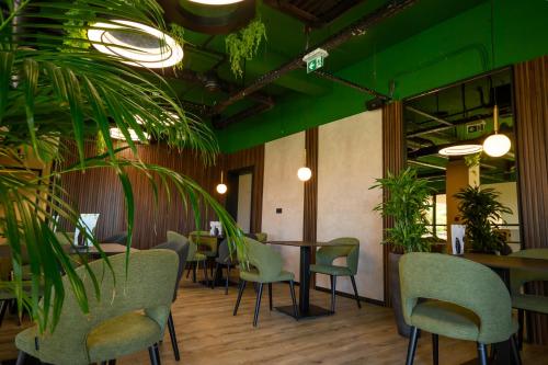 a restaurant with green walls and plants and tables and chairs at Hotel Adore in Ljubljana