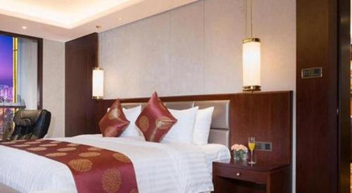 a hotel room with a large bed with pillows at New Century Grand Hotel Xi'an Xizang Building in Xi'an