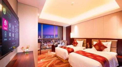 a hotel room with two beds and a flat screen tv at New Century Grand Hotel Xi'an Xizang Building in Xi'an