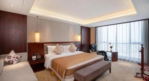a large hotel room with a bed and a chair at New Century Grand Hotel Xi'an Xizang Building in Xi'an