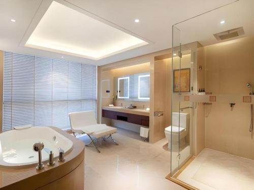 a bathroom with a tub and a toilet and a sink at New Century Grand Hotel Xi'an Xizang Building in Xi'an