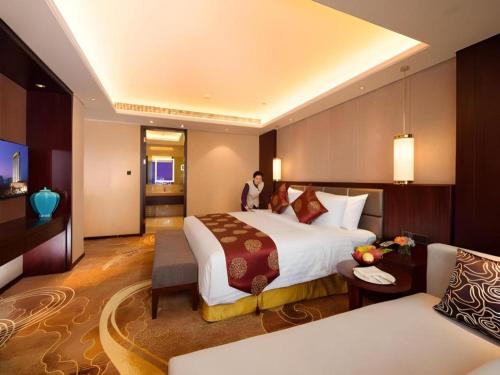 a hotel room with a large bed and a couch at New Century Grand Hotel Xi'an Xizang Building in Xi'an