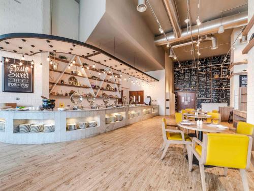 a restaurant with yellow chairs and a dining room at Ibis Styles Dragon Mart Dubai in Dubai