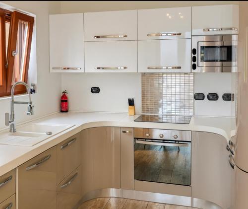 a kitchen with white cabinets and a sink at Casa A&E - Panoramic Lake Orta Views in Oira