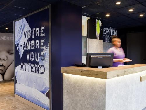 a woman standing behind a counter with a computer at ibis budget Pontault Combault RN4 Marne La Vallée in Pontault-Combault
