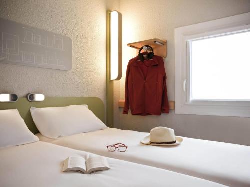 a bedroom with a bed with a hat and glasses on it at ibis budget Pontault Combault RN4 Marne La Vallée in Pontault-Combault