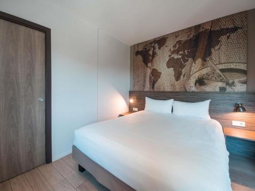 a bedroom with a white bed and a map on the wall at Ibis Styles Hyères Rooftop & Spa in Hyères