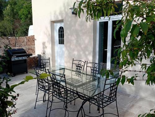 a glass table and chairs on a patio at Gite La maison du gardien in Marcillac-Vallon