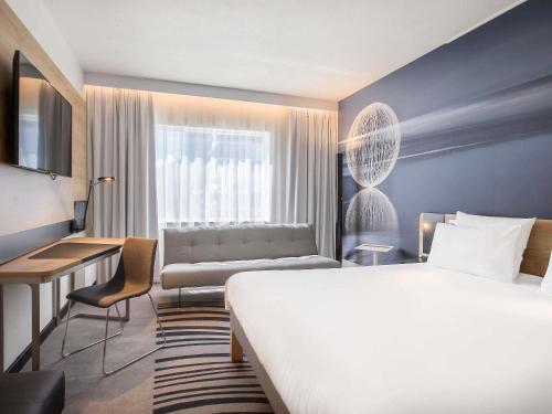 a hotel room with a large bed and a couch at Novotel Wrocław Centrum in Wrocław