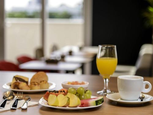 a table with two plates of food and a glass of orange juice at ibis Fortaleza Centro de Eventos in Fortaleza