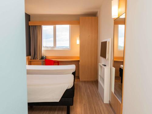 a hotel room with a bed and a tv at ibis Chapeco in Chapecó