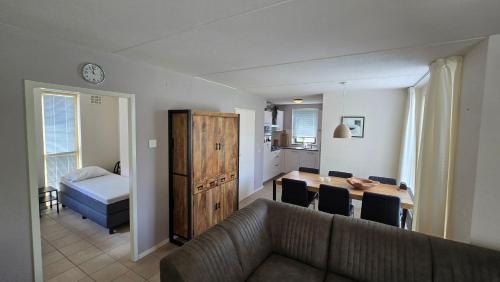 Una sala de estar con un sofá y una mesa de comedor. en Vakantiewoning maas en waal 90, en Ewijk