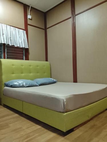 a bedroom with a green bed with blue pillows at Benteng Taman Negara in Jerantut