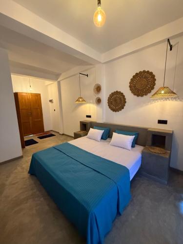 a bedroom with a large bed with a blue blanket at Little jay"s villa in Batigama