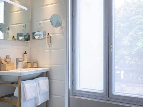 a bathroom with a sink and a window at Mercure Paris Saint Cloud Hippodrome in Saint-Cloud
