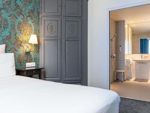 a bedroom with a white bed and a bathroom at Mercure Paris Saint Cloud Hippodrome in Saint-Cloud