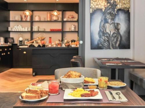 a table with breakfast food on it in a restaurant at Mercure Paris Saint Cloud Hippodrome in Saint-Cloud