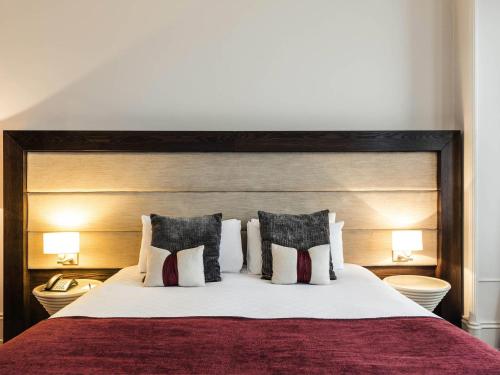 a bedroom with a large bed with pillows at Mercure Aberdeen Caledonian Hotel in Aberdeen