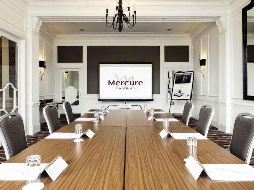 a conference room with a long table and a projection screen at Mercure Aberdeen Caledonian Hotel in Aberdeen