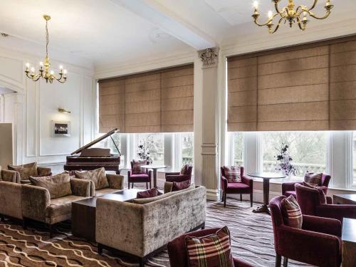 a living room with a couch and a piano at Mercure Aberdeen Caledonian Hotel in Aberdeen