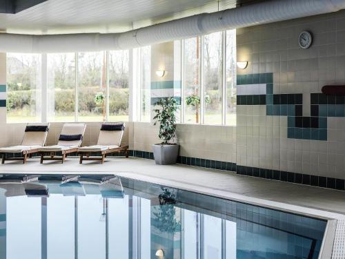 a swimming pool in a building with chairs next to a pool at Mercure Daventry Court Hotel in Daventry