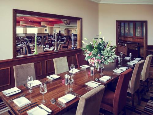 a long wooden table in a restaurant with chairs at Mercure Daventry Court Hotel in Daventry
