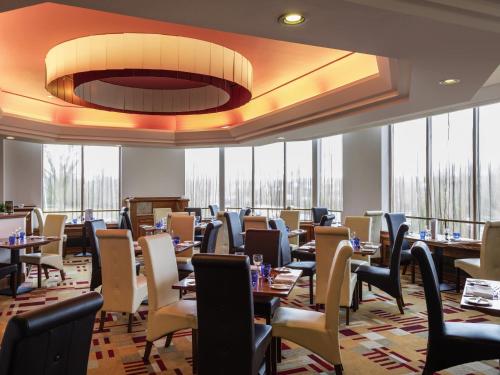 a dining room with tables and chairs and windows at Mercure Daventry Court Hotel in Daventry