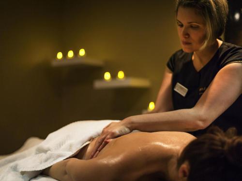 a woman giving a man a massage on a bed at Mercure Dartford Brands Hatch Hotel & Spa in Ash