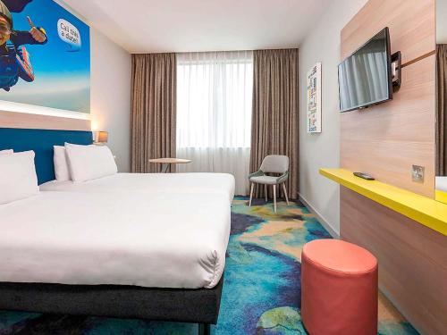 a hotel room with a bed and a tv at ibis Styles London Heathrow Airport in Hillingdon