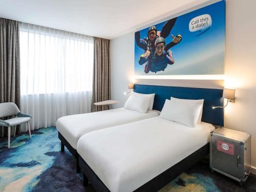 a hotel room with two beds and a poster on the wall at ibis Styles London Heathrow Airport in Hillingdon