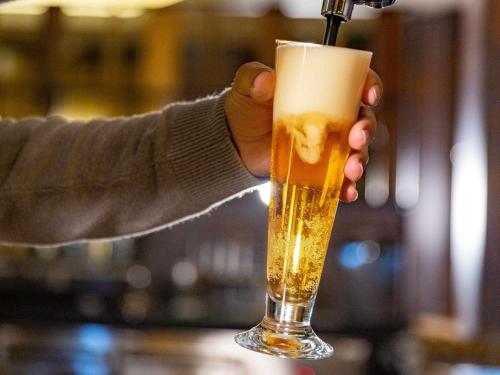 a person is holding a glass of beer at Ibis Styles Lisboa Centro Liberdade NE in Lisbon