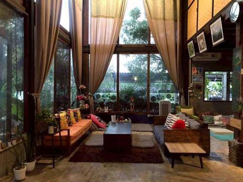 a living room filled with furniture and a large window at Laanrablom Bed&Breakfast in Sara Buri